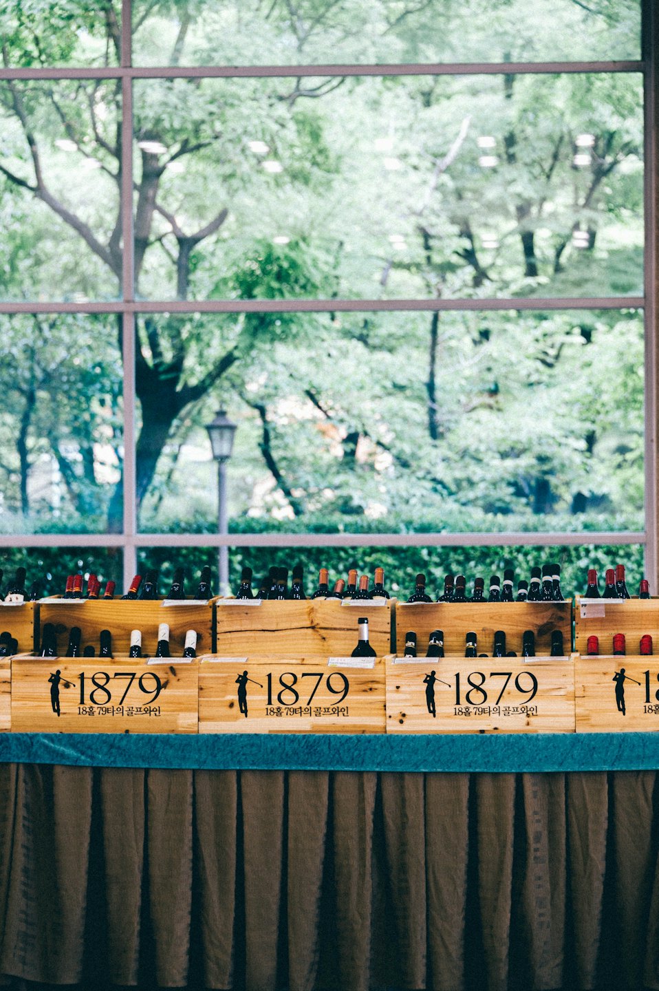 Wine bottles in wooden crates sitting on a patterned tablecloth.