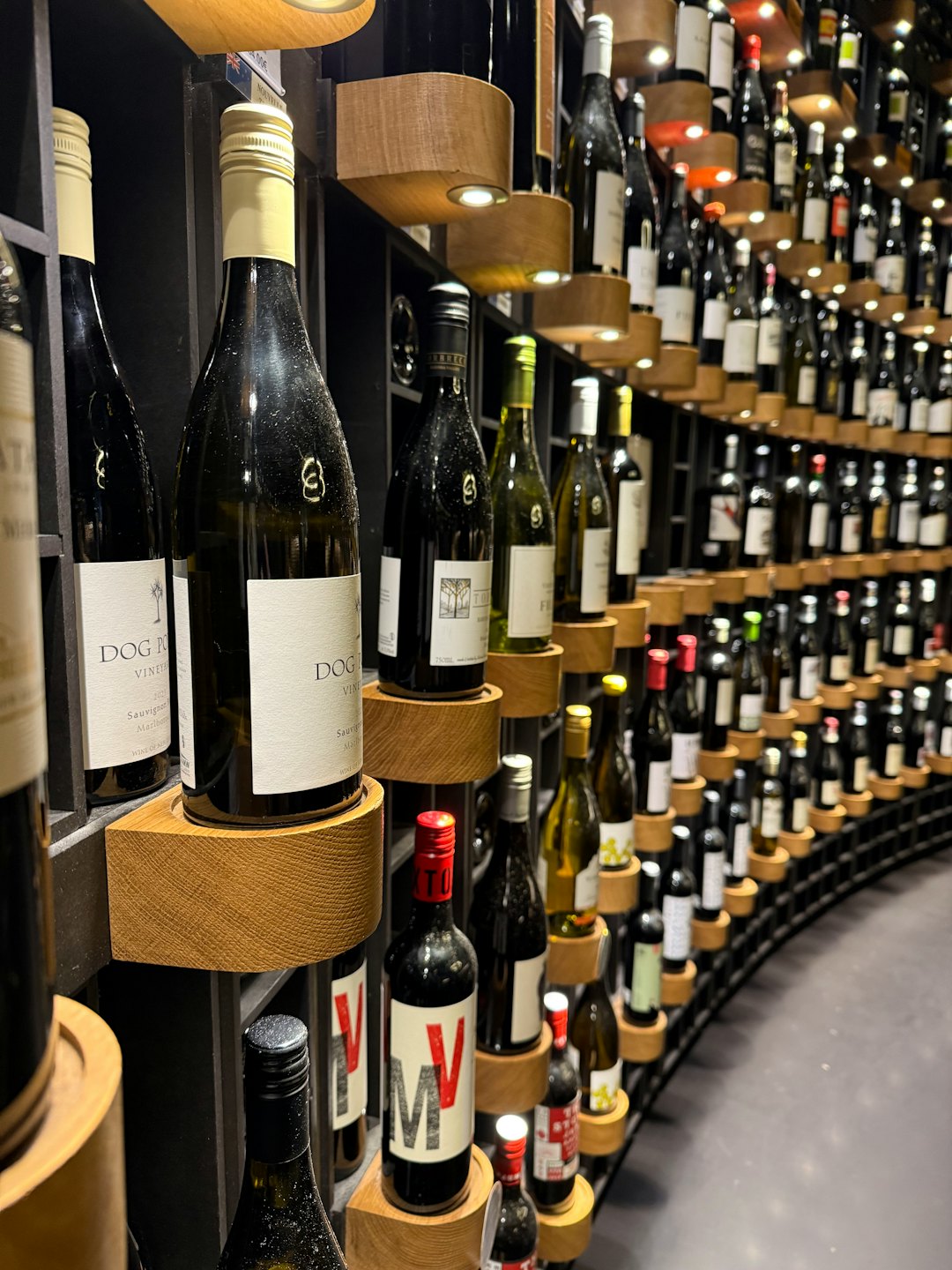 Curved wall display holding numerous wine bottles with visible labels.