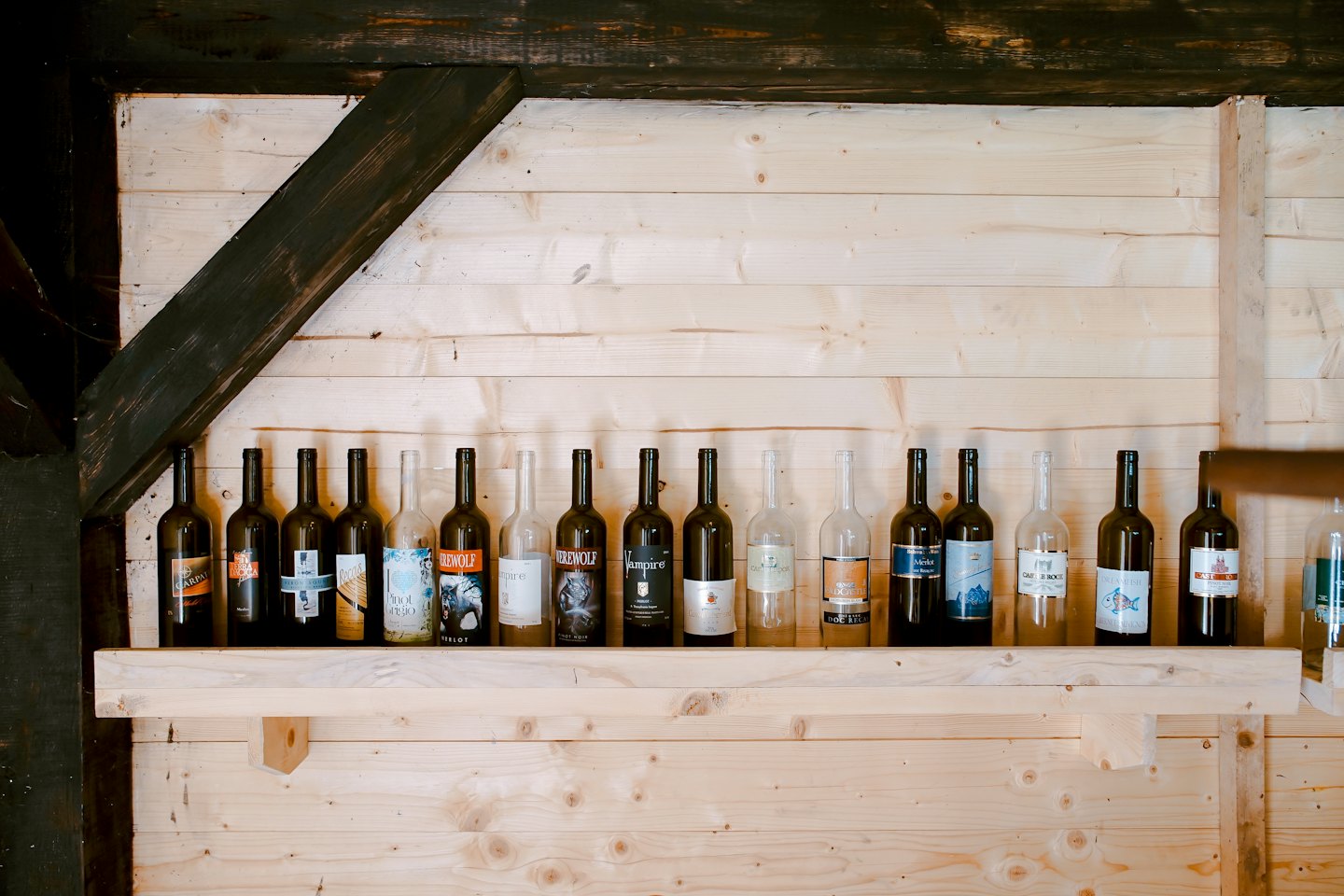 Wine bottles are arranged on a rustic wooden shelf.