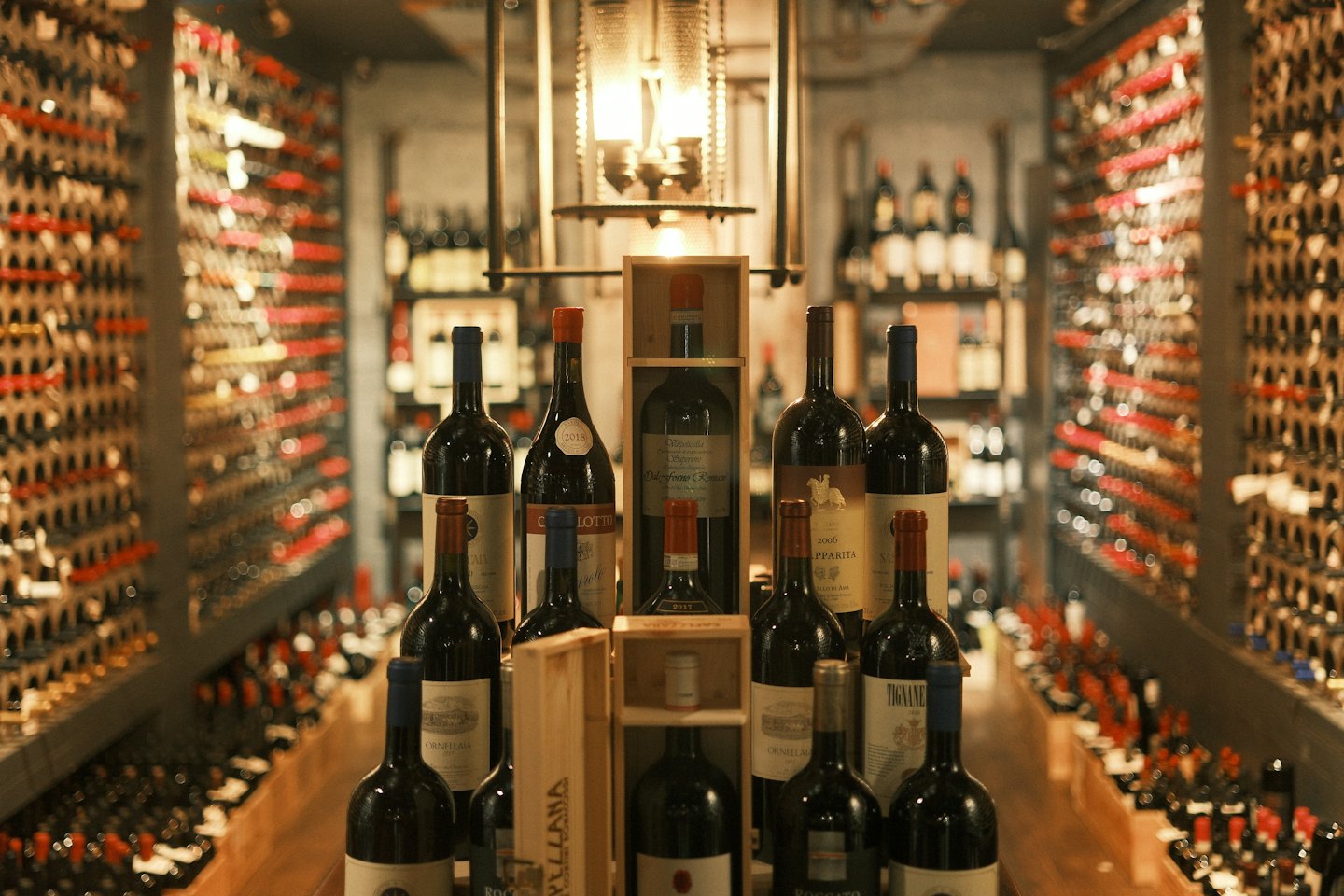 Rows of wine bottles rest on wooden racks in a cellar.